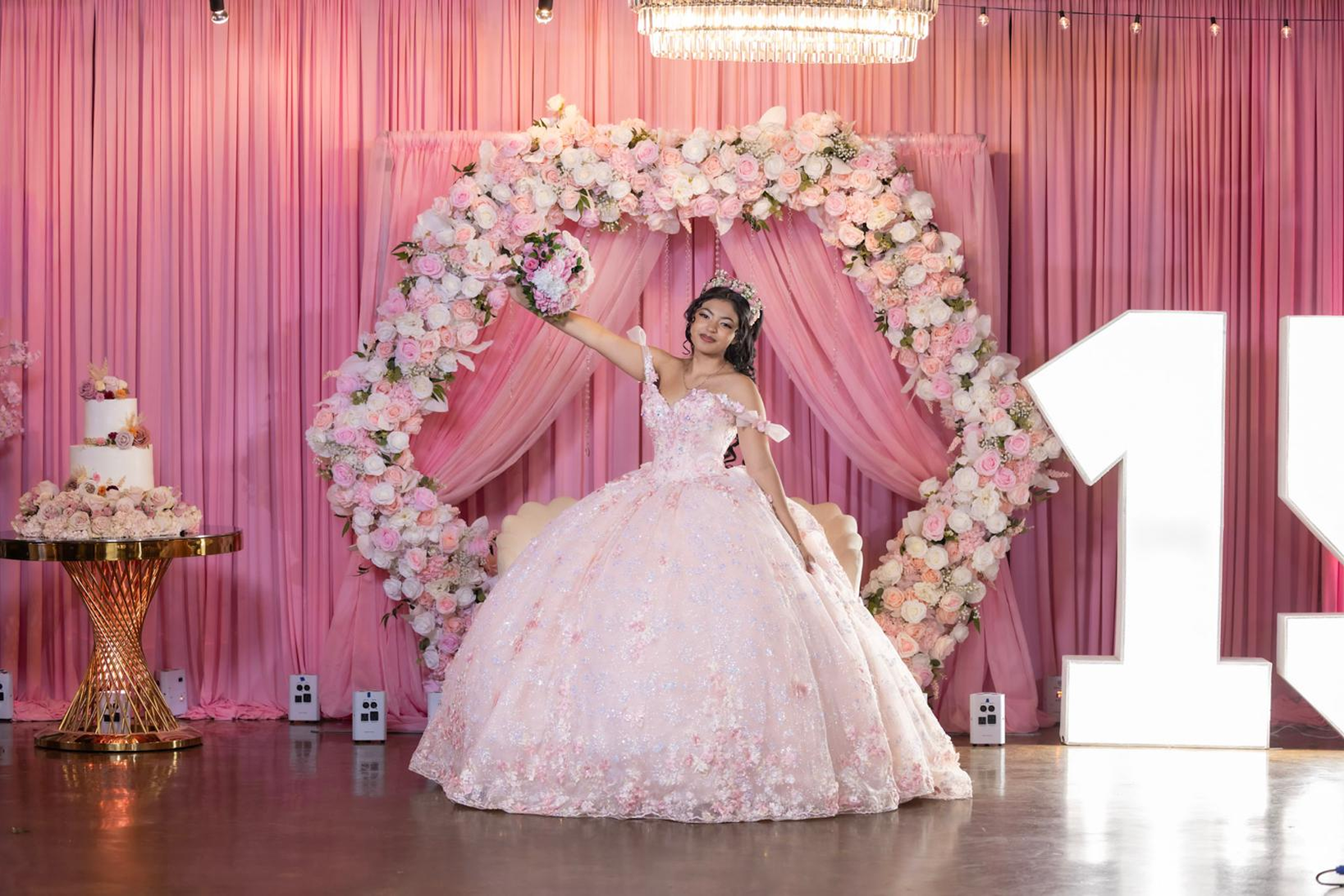 Pink quinceañera stage with floral ring and marquee numbers