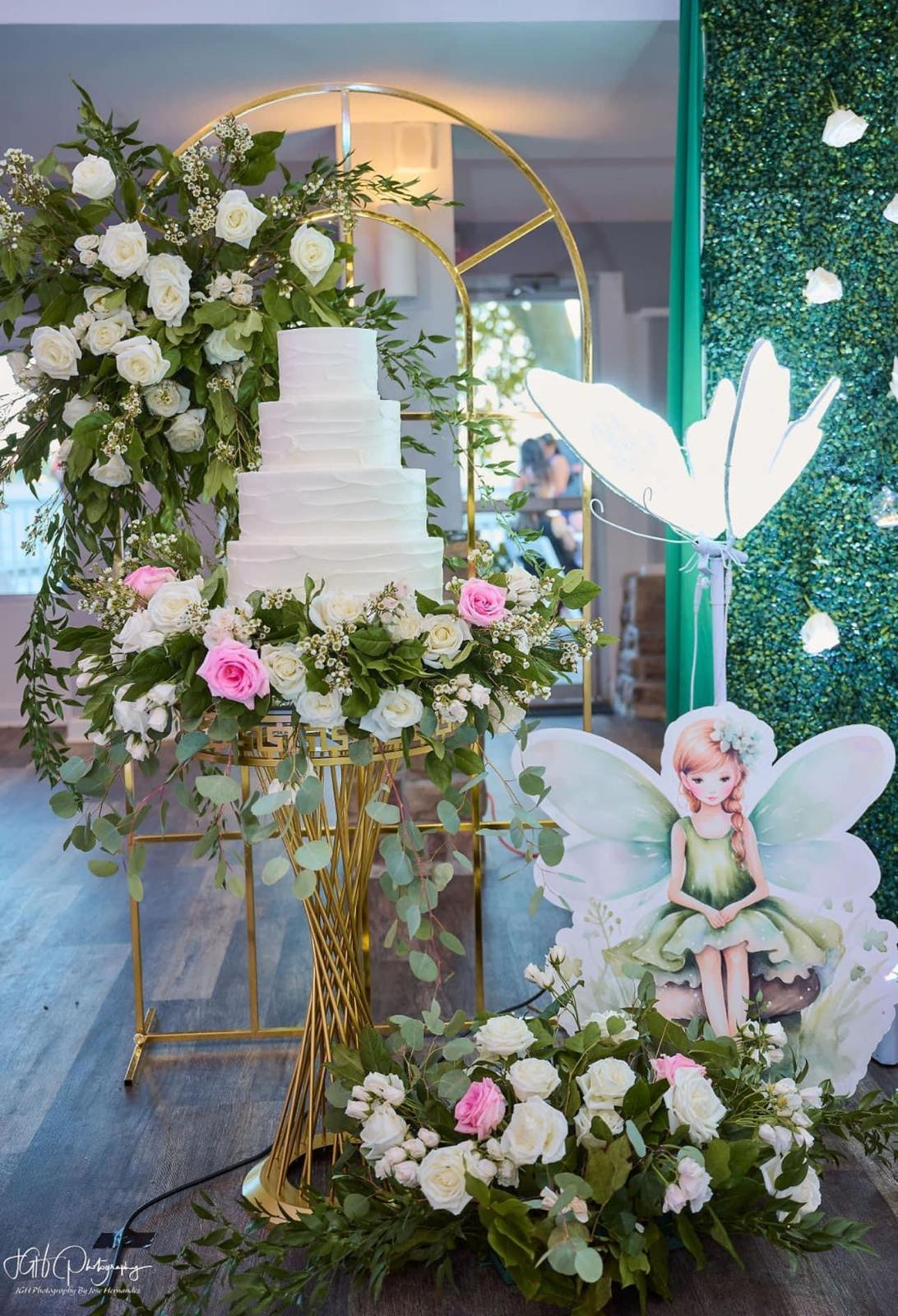 Fairy-themed cake display with florals and greenery