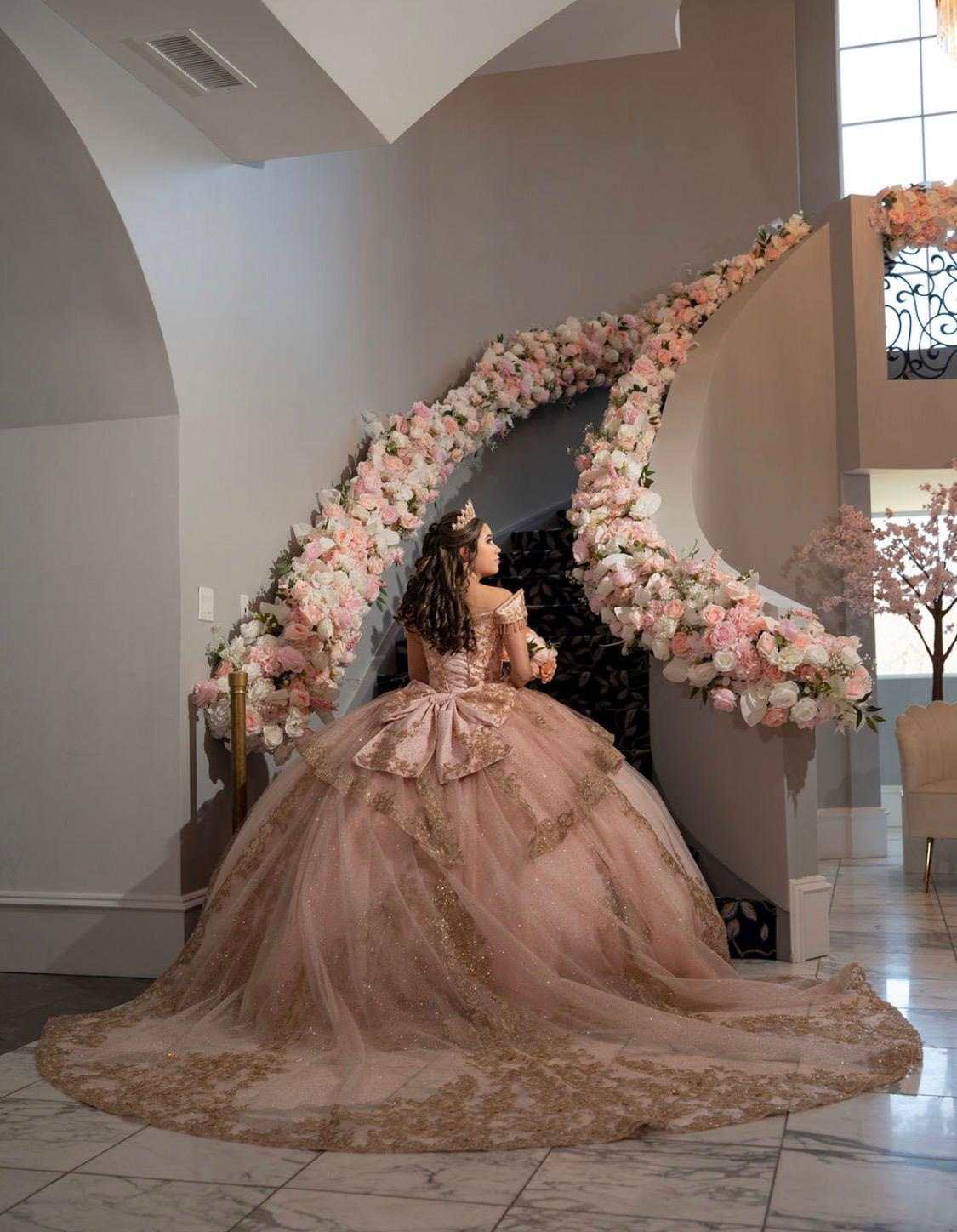 Quinceañera by a blush floral staircase arch