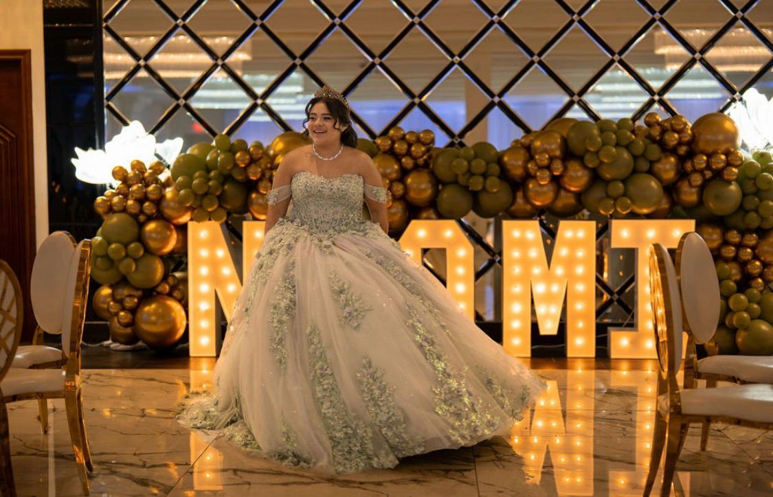 Celebrant in front of a gold balloon marquee backdrop