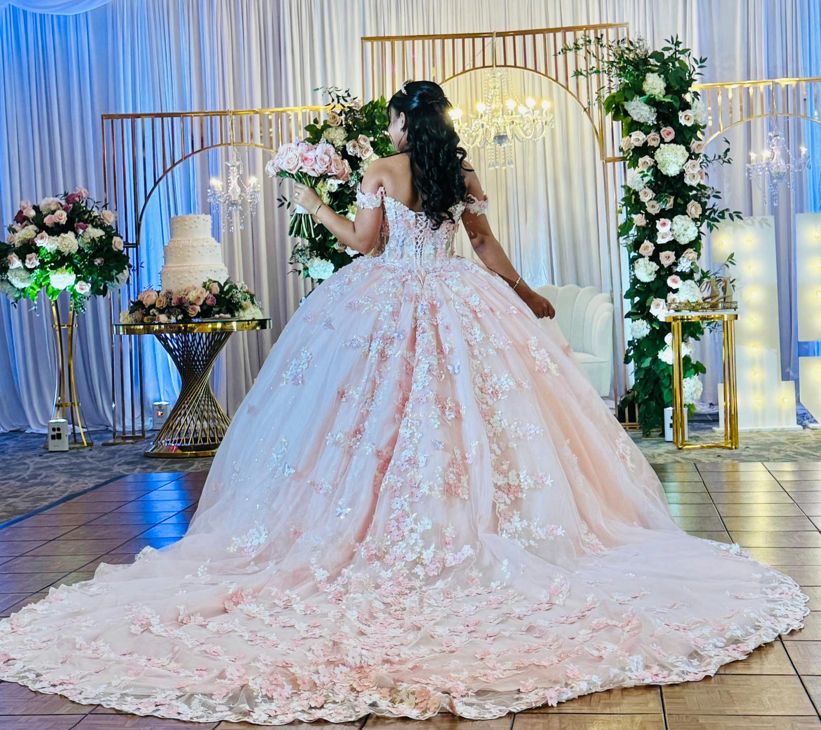 Blush ball gown in front of a floral chandelier arch